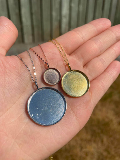 3 circle pendants in 3 different sizes displayedin palm of hand. Meant to be filled with ashes or breastmilk.