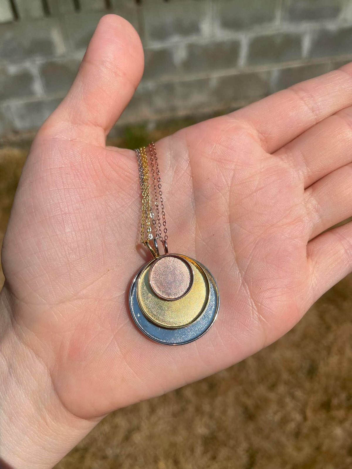 3 circle pendants in 3 different sizes displayed stacked on top of eachother. Meant to be filled with ashes or breastmilk.