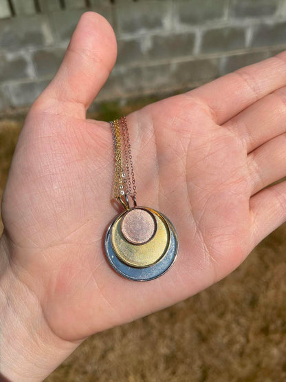 3 circle pendants in 3 different sizes displayed stacked on top of eachother. Meant to be filled with ashes or breastmilk.