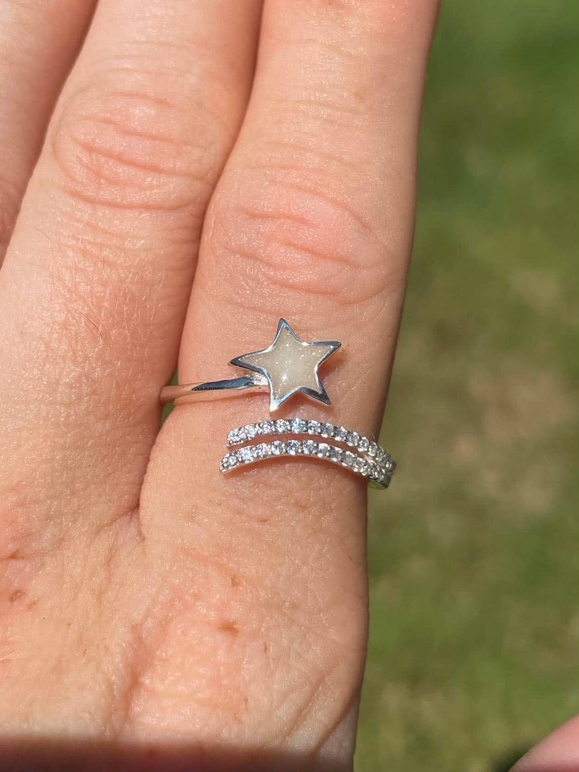 Close-up of a shooting star breastmilk ring on finger filled with preserved breastmilk resin, featuring a delicate star-and-trail design that symbolizes the strength and love found through motherhood.